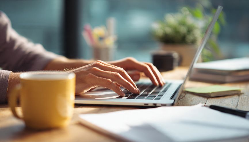 Mãos digitando em um teclado, simbolizando a criação de marketing de conteúdo.
