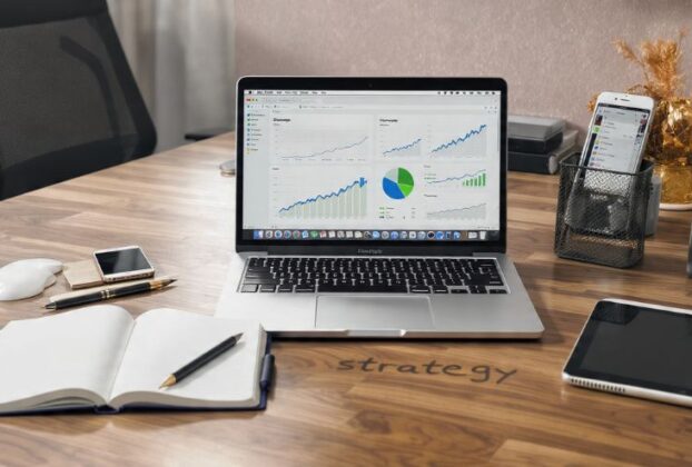 Mesa de trabalho organizada com laptop e ferramentas digitais, simbolizando a produtividade no marketing digital.