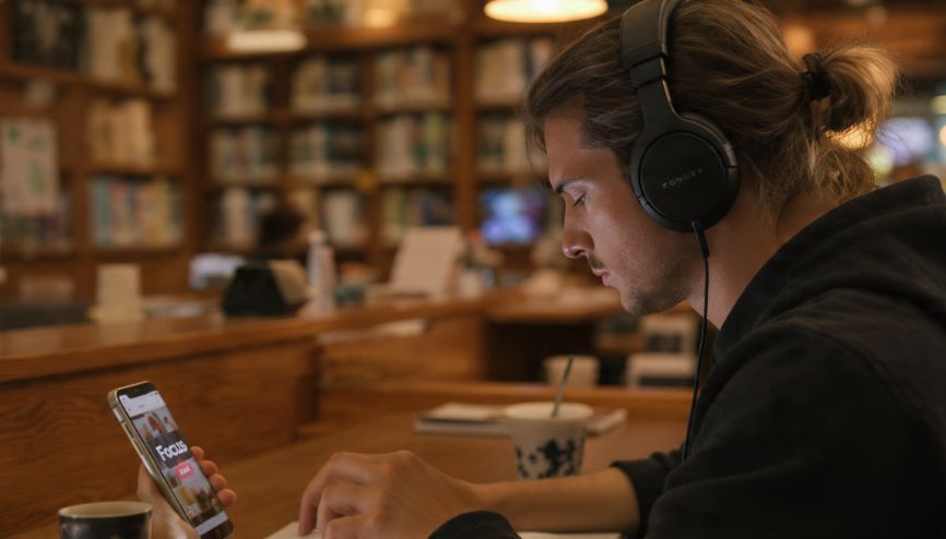 Pessoa utilizando fones de ouvido e smartphone para trabalho profundo, aumentando a produtividade no celular.